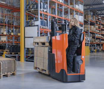 Stoccatore elettrico con operatore a bordo in piedi Toyota durante il trasporto del carico